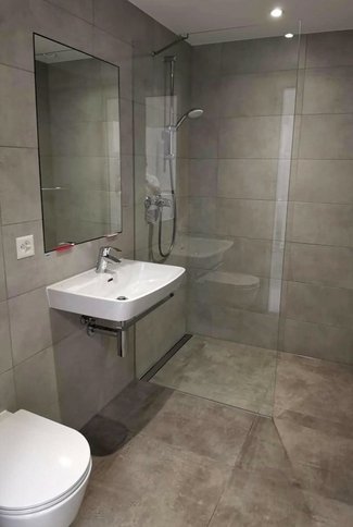 Foto einer Nasszelle, Dusche mit Glaswand, Lavabo, Spiegel und Toilette